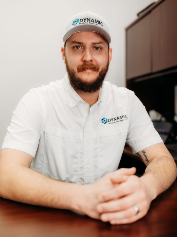 A man smiling wearing a Dynamic Mobile Storage hat